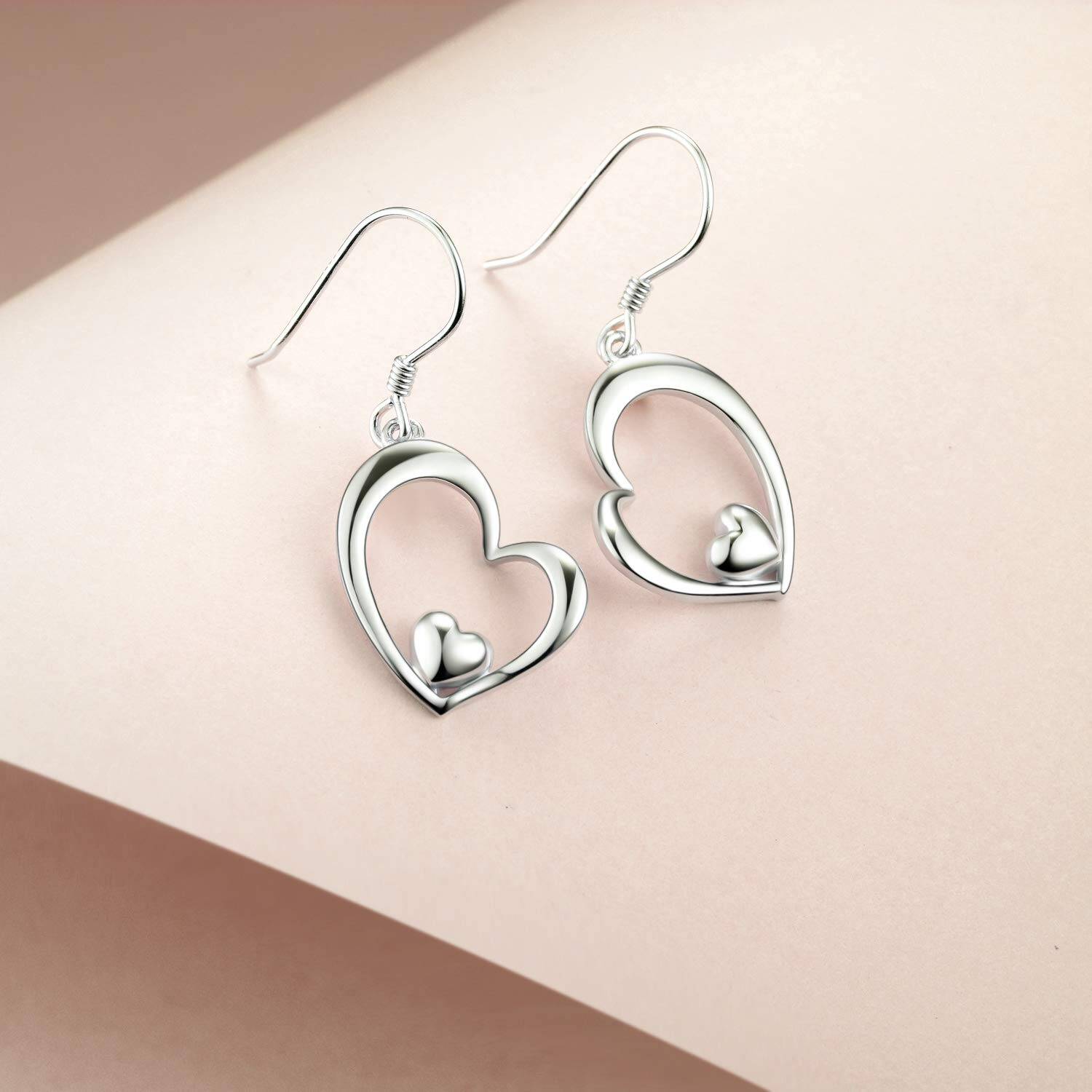 Silver heart-shaped earrings on a beige background