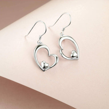Silver heart-shaped earrings on a beige background