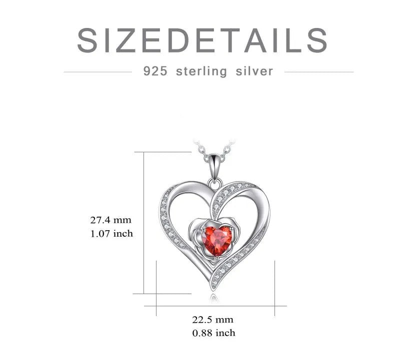 Heart-shaped silver pendant with a red gemstone and measurements on a white background