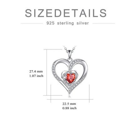 Heart-shaped silver pendant with a red gemstone and measurements on a white background