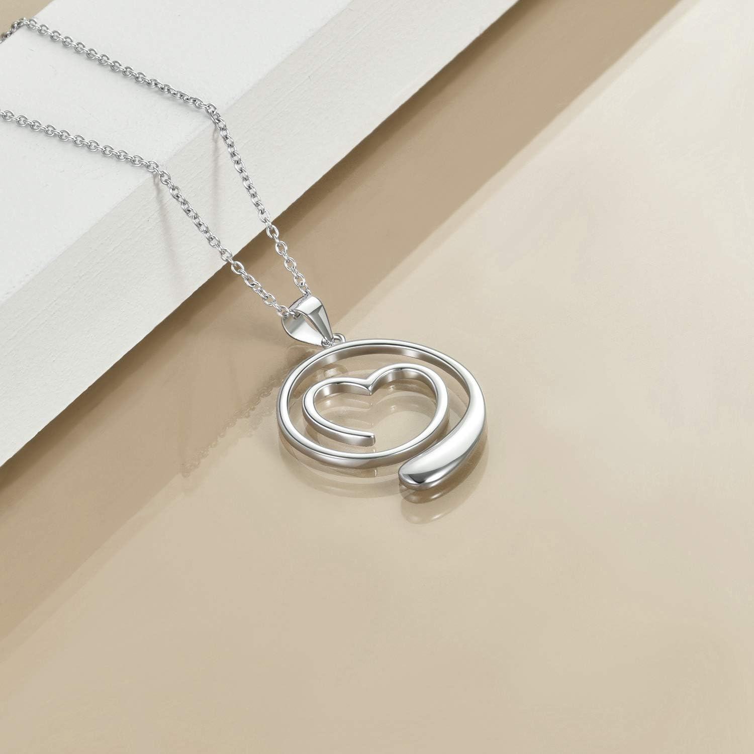 Silver necklace with a heart and wave design pendant on a beige surface