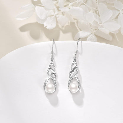 Silver earrings with pearls on a white surface with white flowers in the background