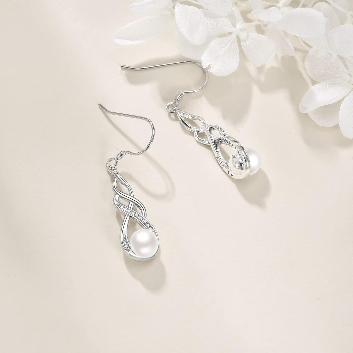 Silver earrings with a pearl on a light background