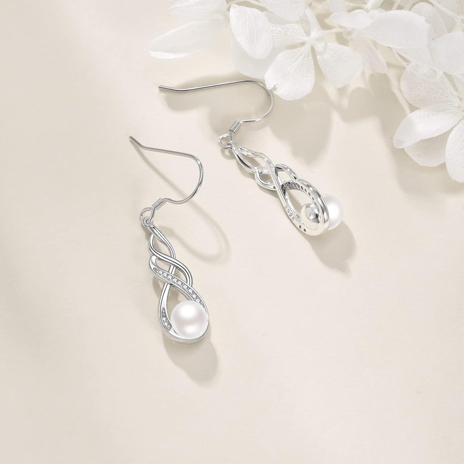 Silver earrings with a pearl on a light background