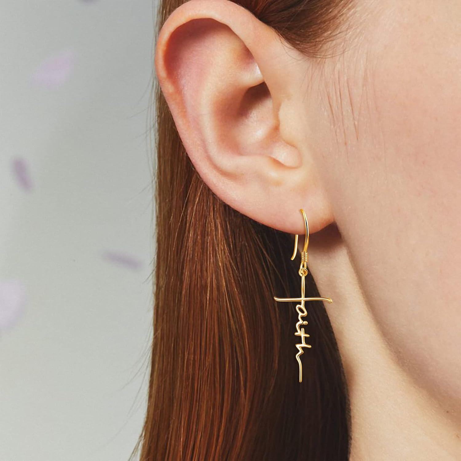 Gold 'Faith' earrings worn by a person with a neutral background