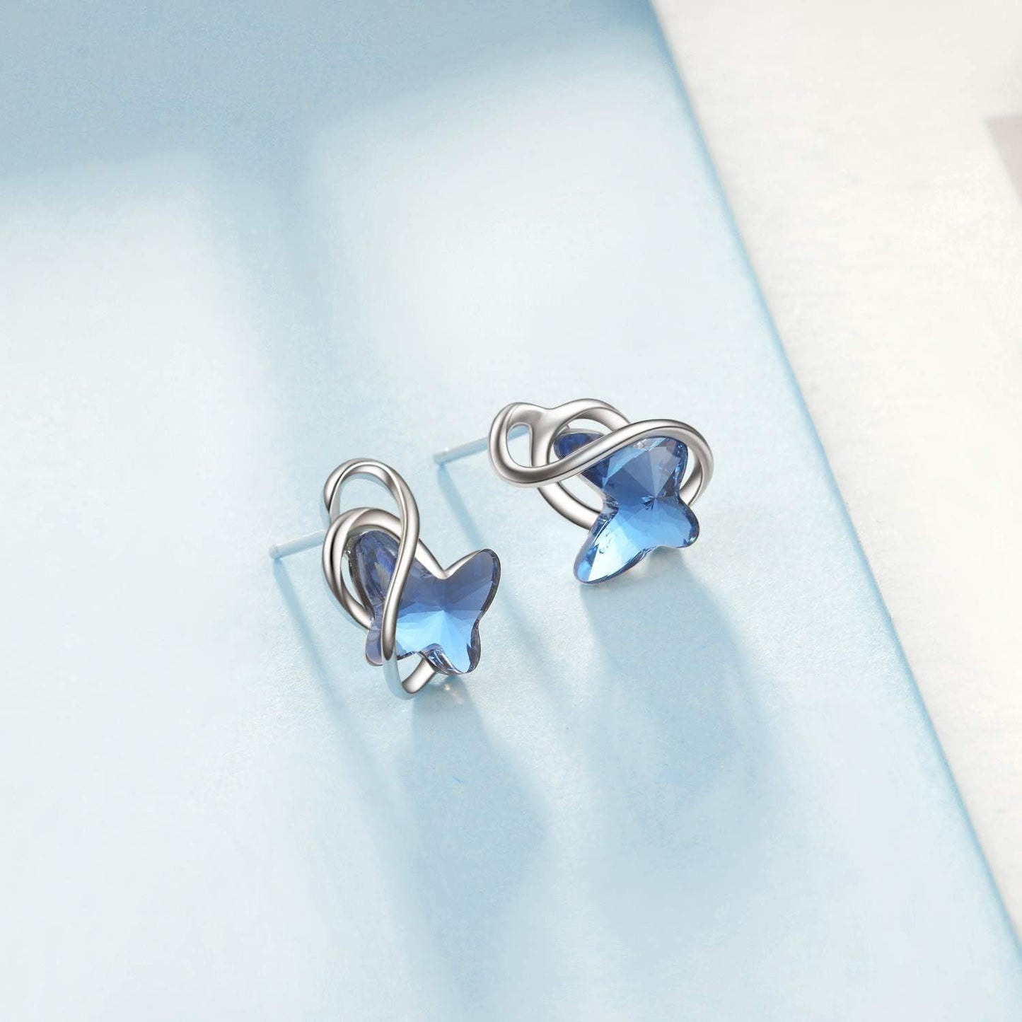 Pair of silver earrings with blue gemstones on a light blue background