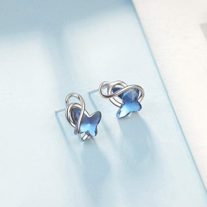 Pair of silver earrings with blue gemstones on a light blue background