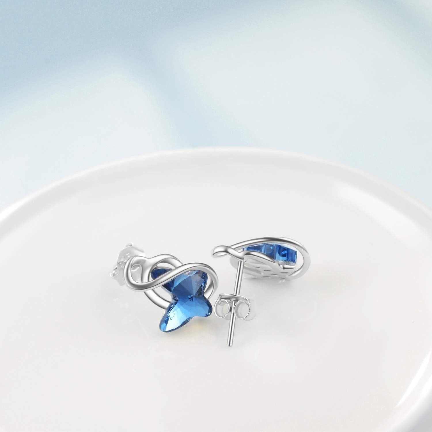 Pair of silver earrings with blue gemstones on a white dish with a light blue background