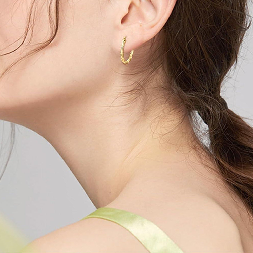 Close-up of a woman wearing a gold hoop earring against a neutral background