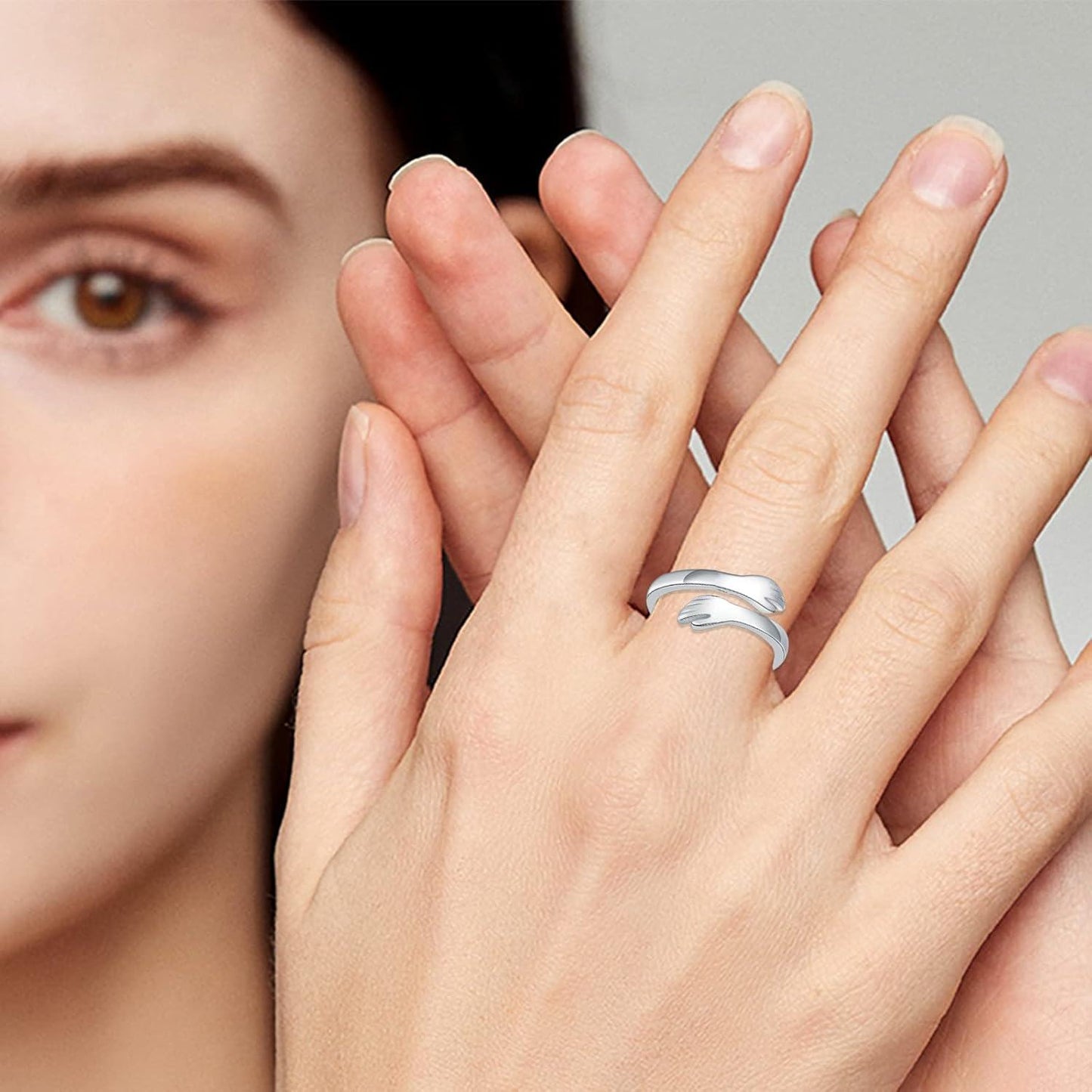 Close-up of a hand wearing a silver ring with a blurred face in the background