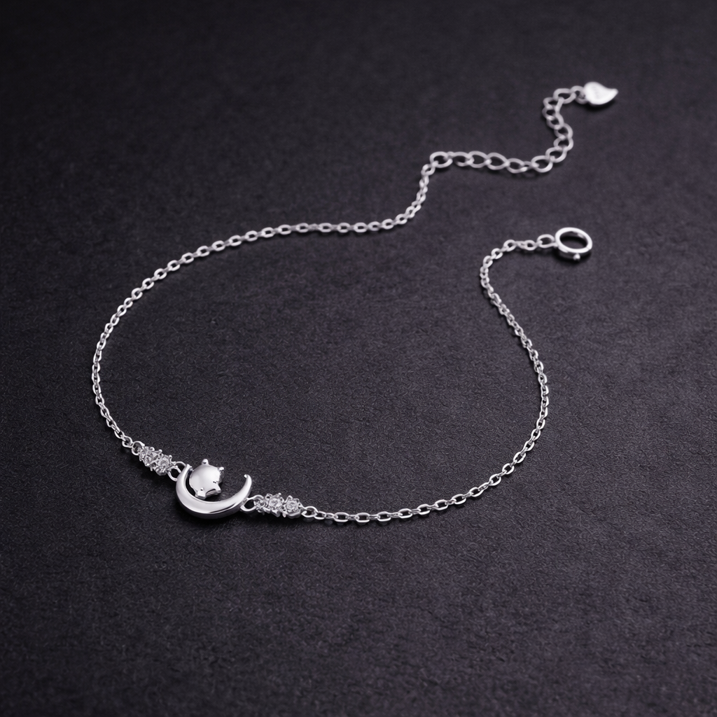 Silver bracelet with a moon and star design on a dark background