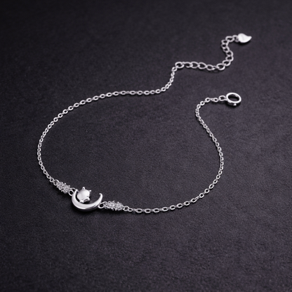 Silver bracelet with a moon and star design on a dark background