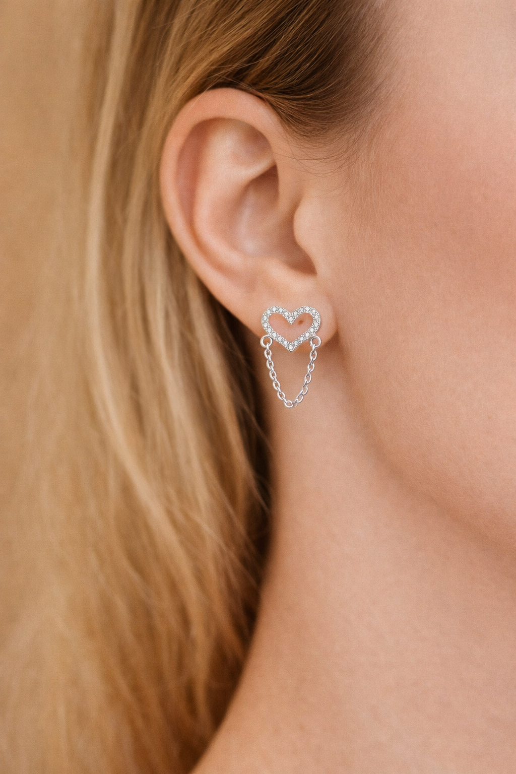 Close-up of a person wearing a silver heart-shaped earring.