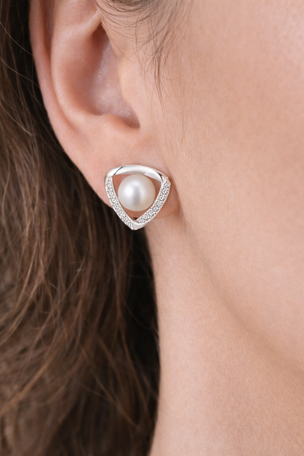 Pearl earring worn on an ear with a neutral background