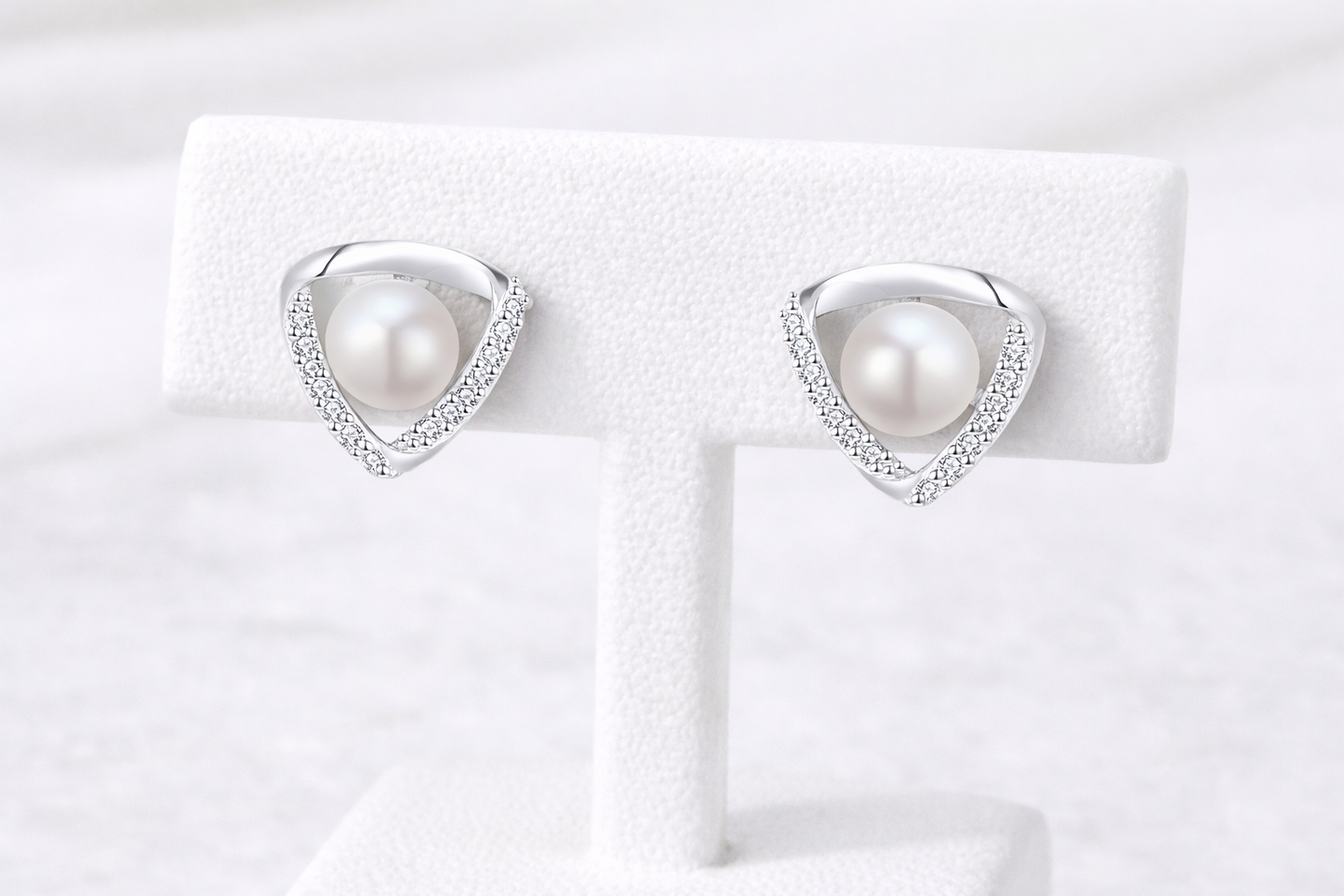 Pearl earrings on a white display card with a white background
