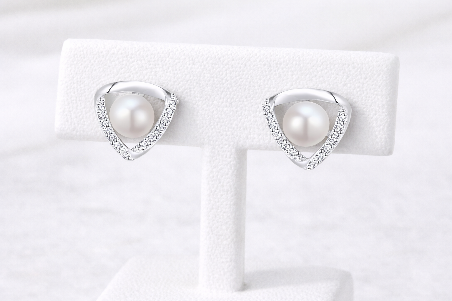 Pearl earrings on a white display card with a white background