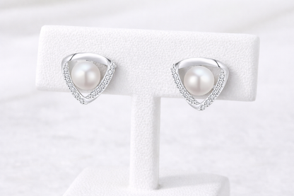 Pearl earrings on a white display card with a white background