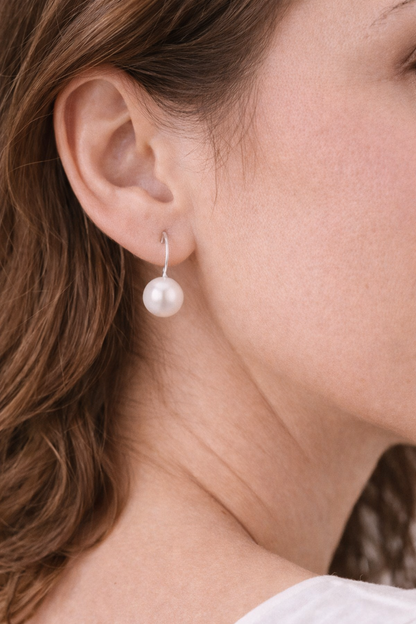 Pearl earring worn by a person with brown hair.