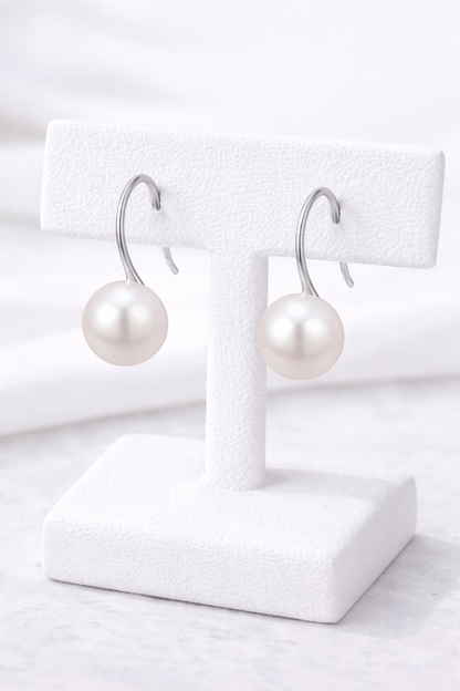 Pearl earrings on white earring stands with a white background