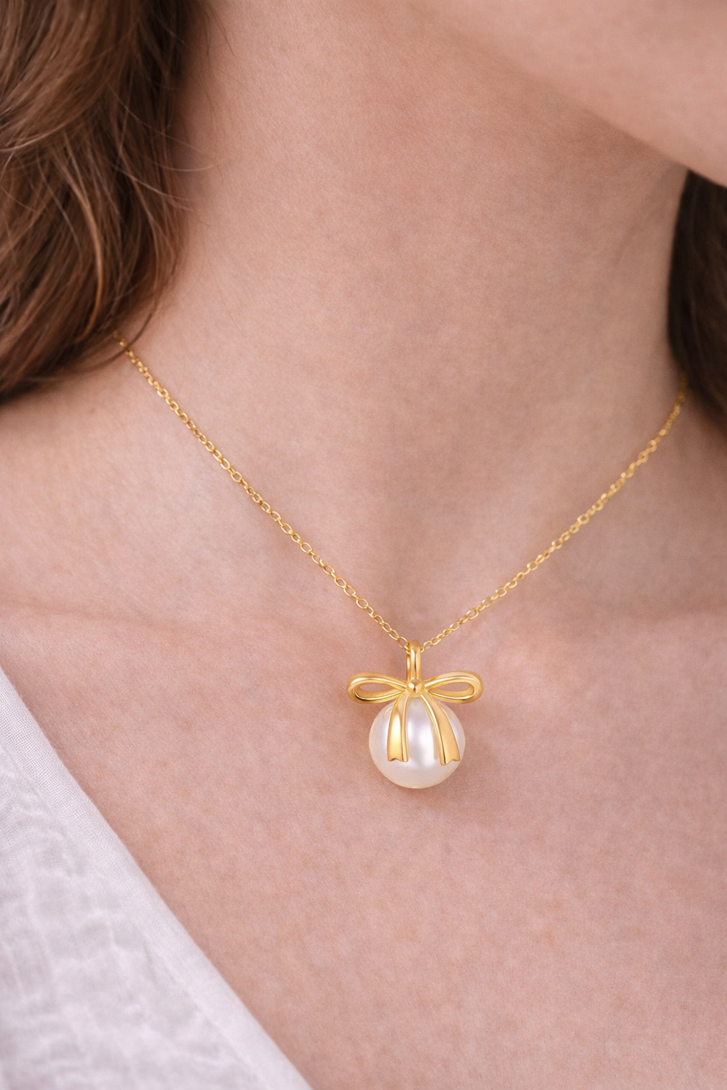 Gold necklace with a pearl pendant worn by a person