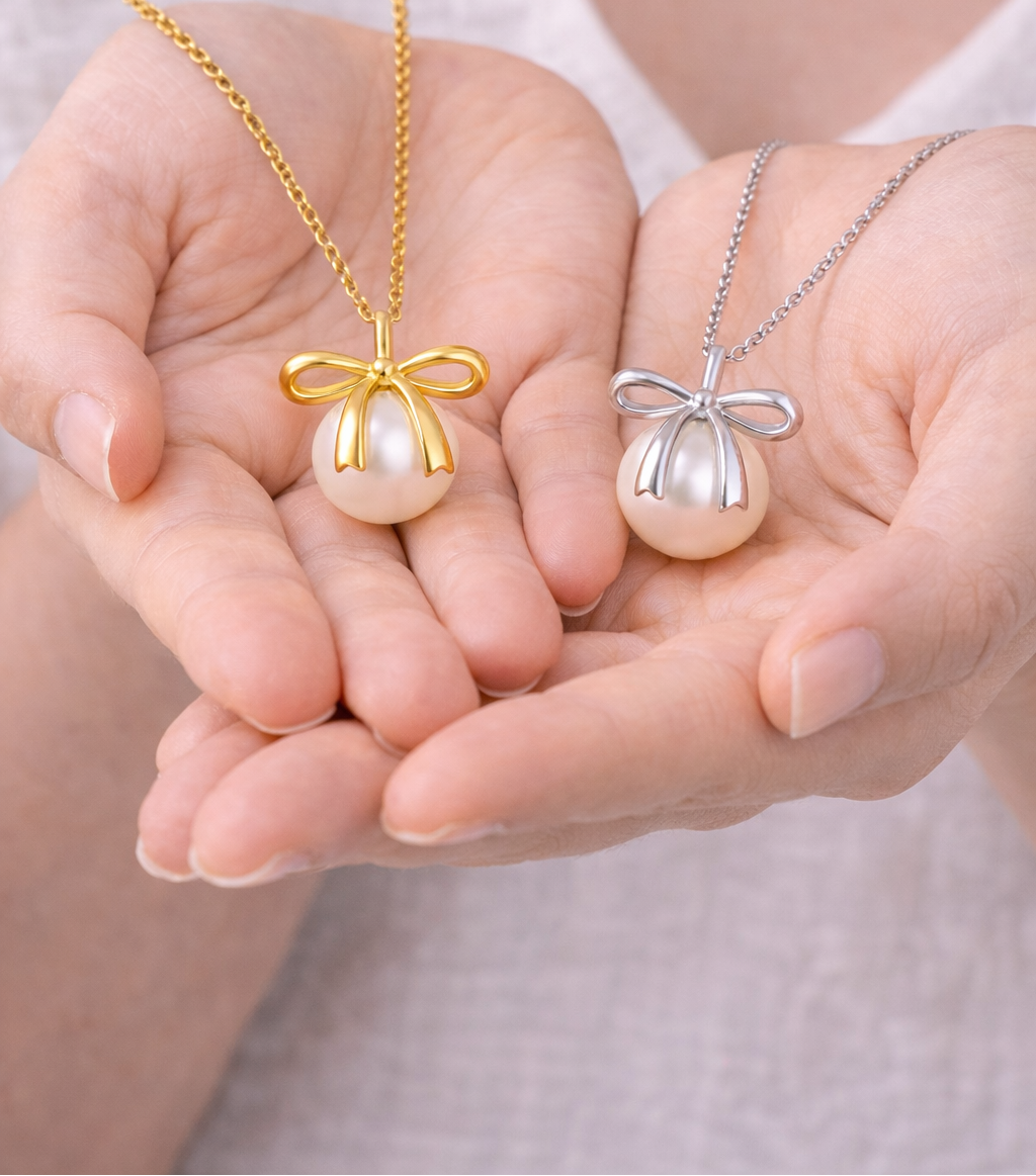 Two gold and silver pearl pendants held in hands against a neutral background