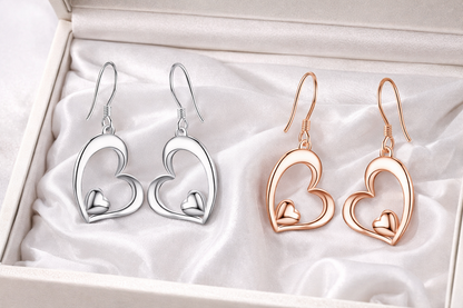 Heart-shaped earrings in silver and rose gold on a white fabric background