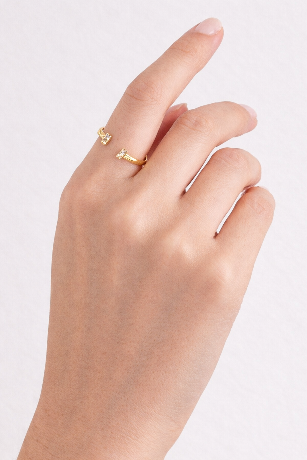 Hand wearing a gold ring on a light background