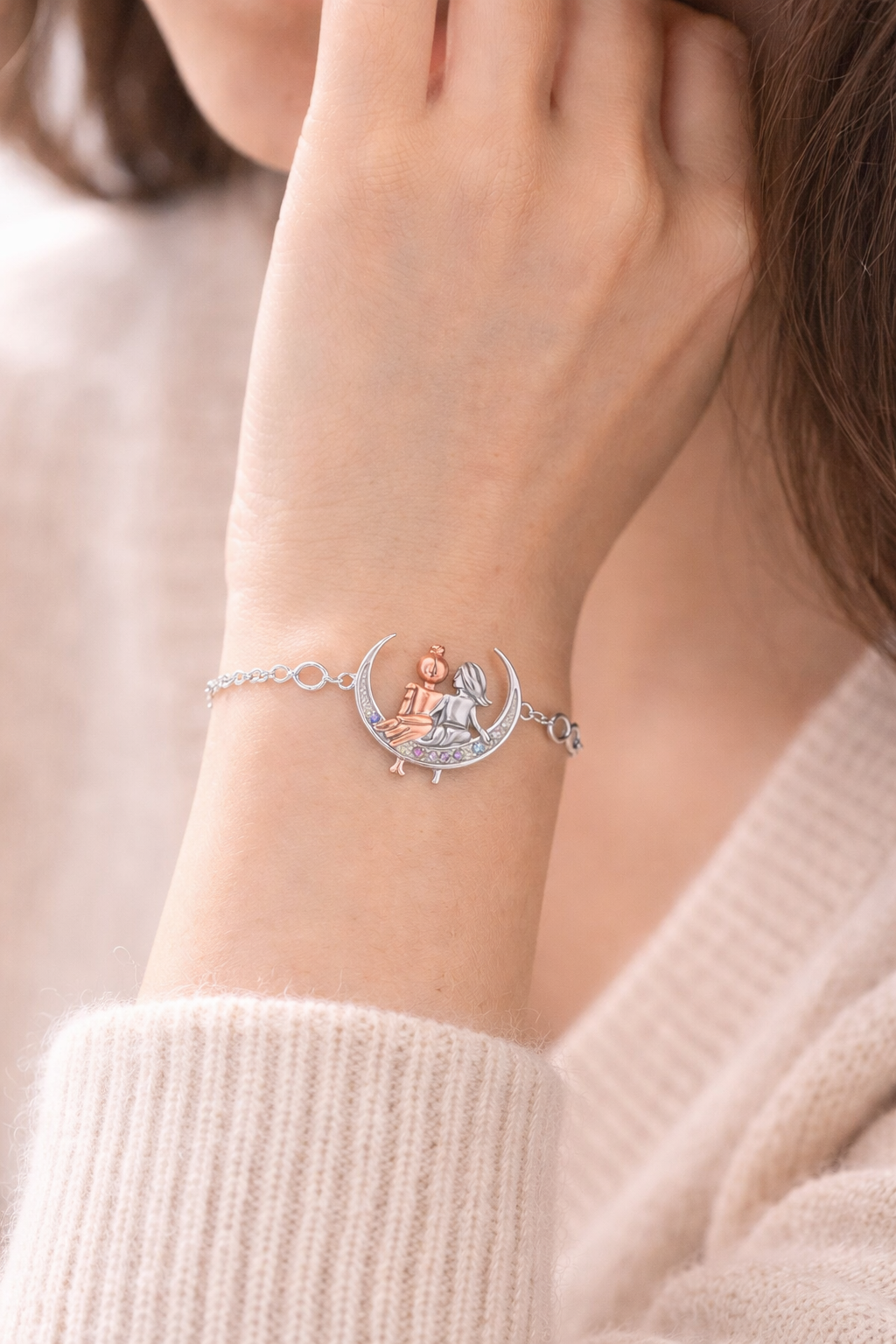 Bracelet with angel design on a wrist, wearing a light pink sweater.