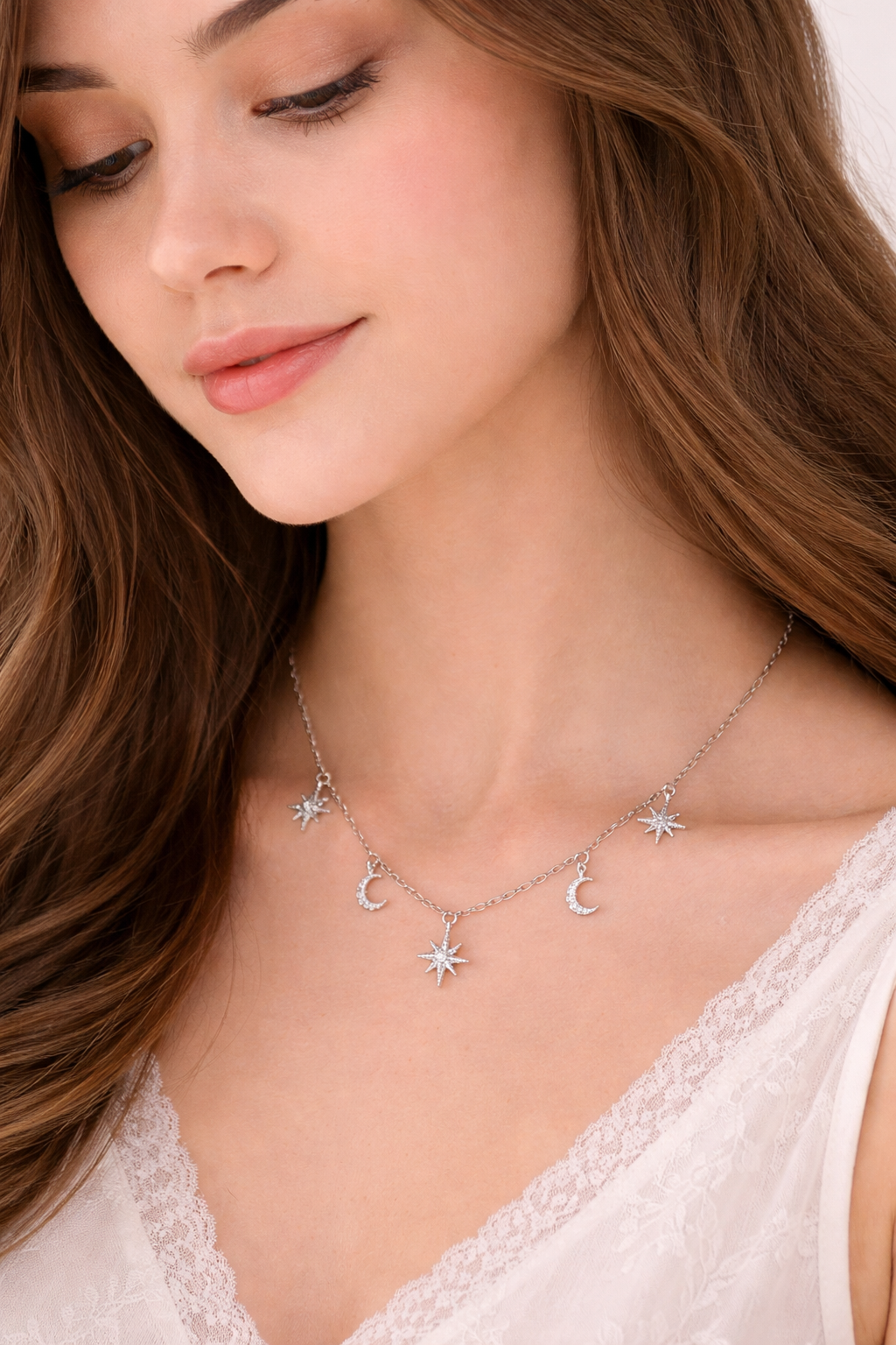 Woman wearing a silver necklace with star and moon charms.