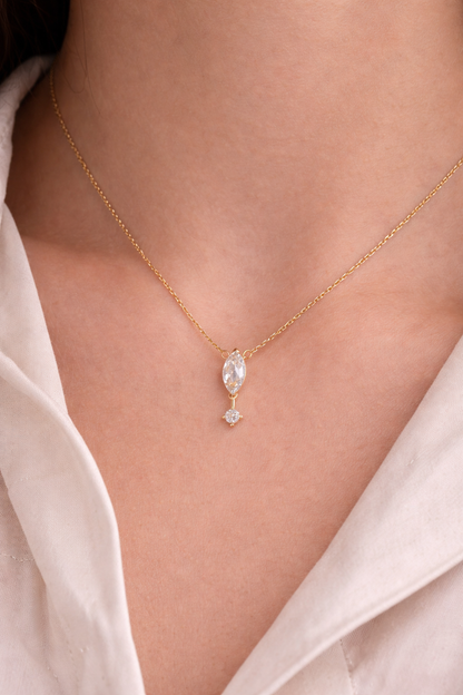 Gold necklace with a pendant on a person wearing a white shirt.