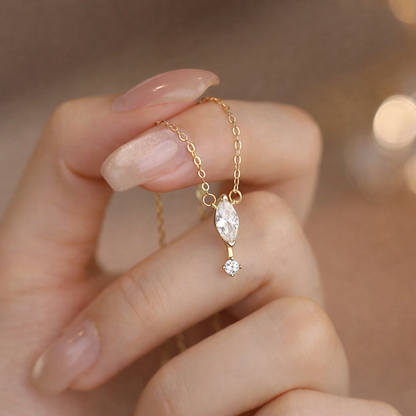 Gold necklace with a pendant held by a hand against a blurred background