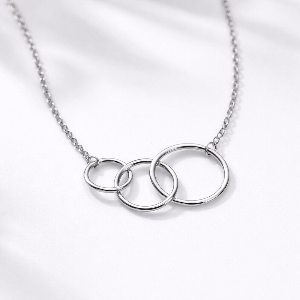 Silver necklace with three interlocking rings on a light gray background