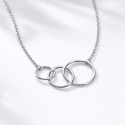 Silver necklace with three interlocking rings on a light gray background