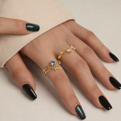 Hand wearing a gold ring with gemstones on a neutral background