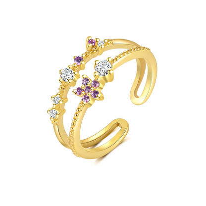 Gold ring with purple and clear gemstones on a white background