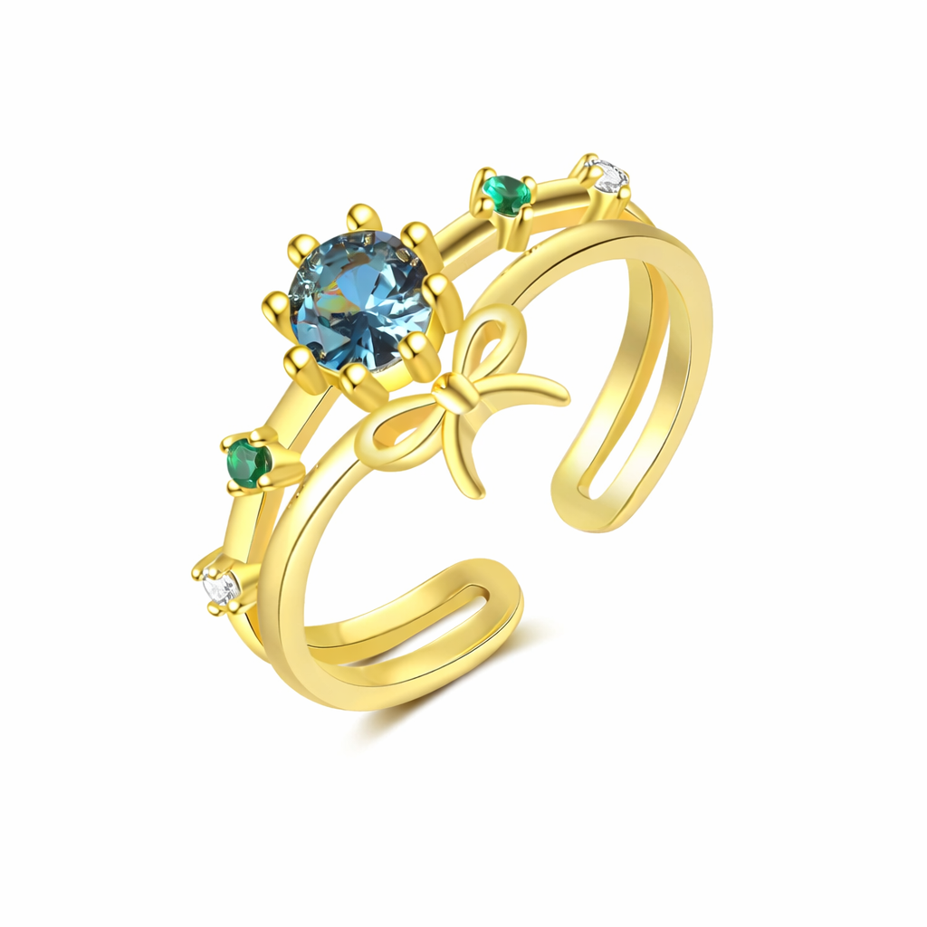 Gold ring with blue gemstone and emeralds on a white background