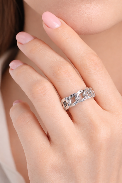 Close-up of a hand wearing a silver ring with a diamond on a neutral background