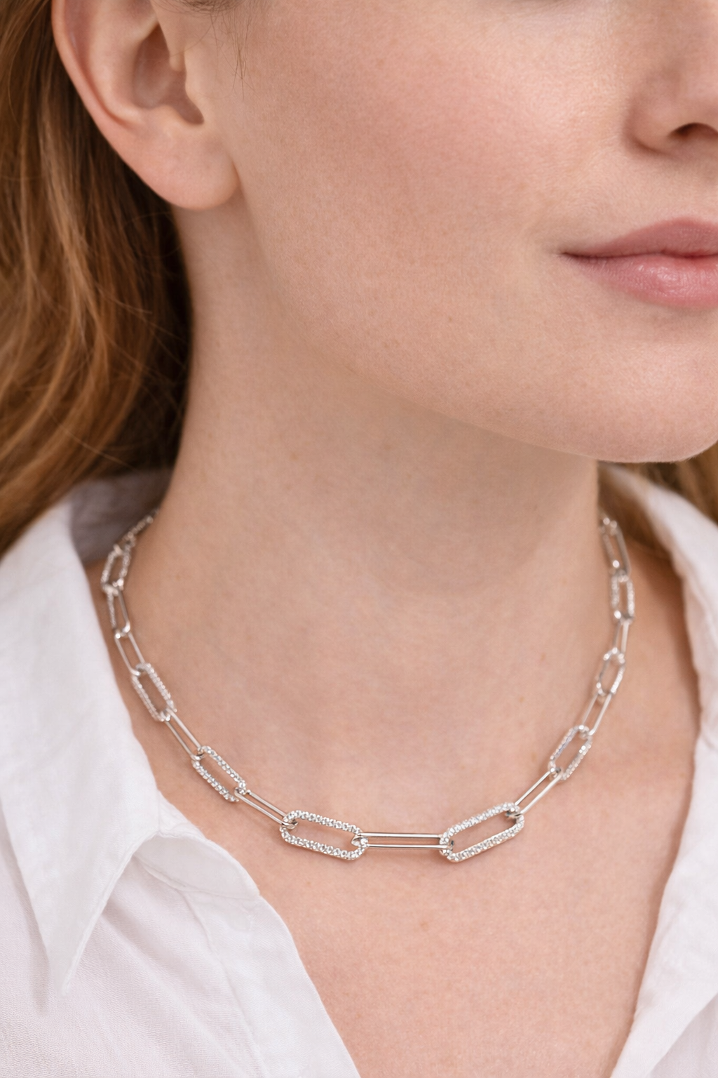 Silver chain necklace worn by a person with a white shirt