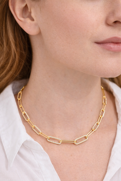 Gold chain necklace worn by a person with a white shirt