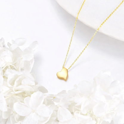 Gold heart-shaped necklace on a white background with flowers