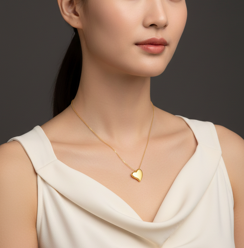 Woman wearing a gold heart-shaped necklace against a dark background