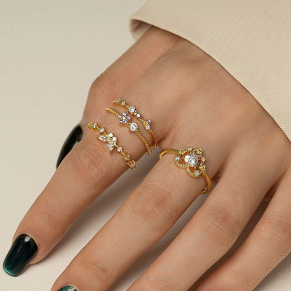 Hand wearing two gold rings with gemstones on a beige background