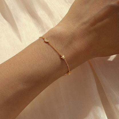 Gold bracelet on a wrist against a beige background