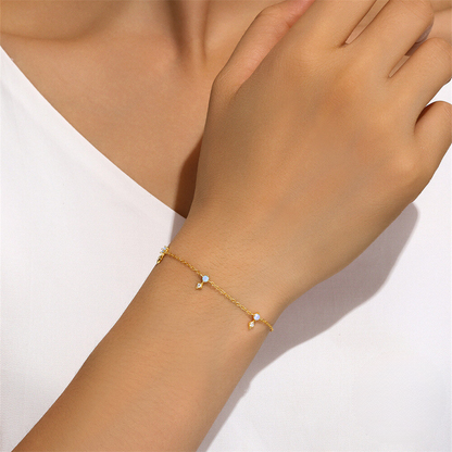 Gold bracelet with small stones on a wrist against a white background