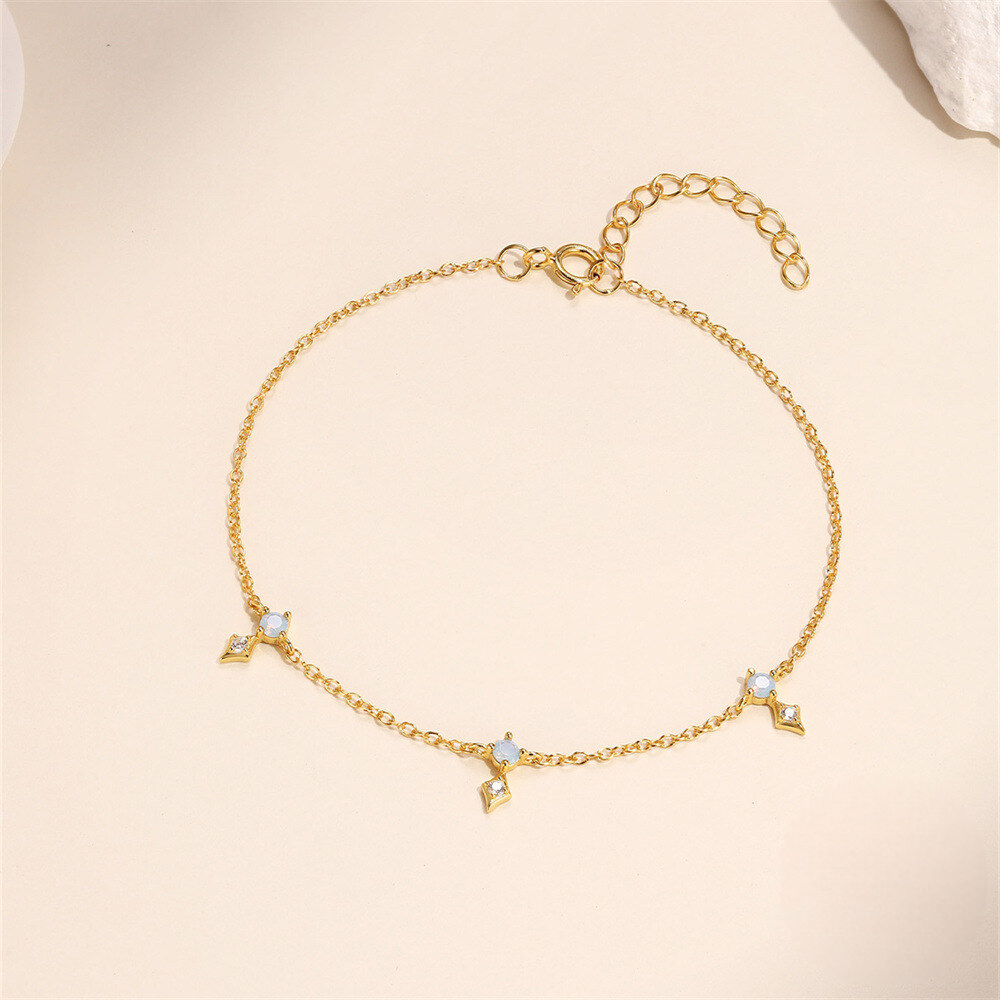 Gold bracelet with star-shaped charms on a beige background