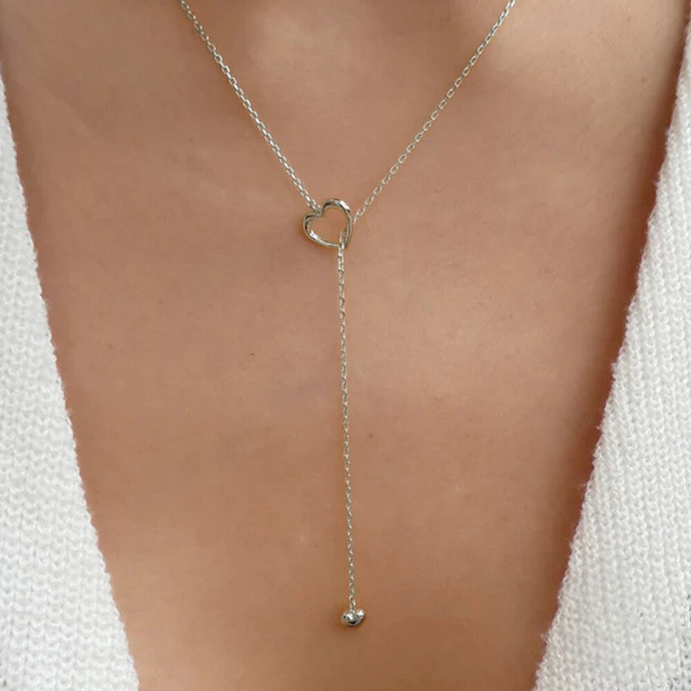 Silver lariat necklace on a person wearing a white top