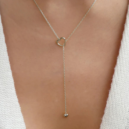 Silver lariat necklace on a person wearing a white top