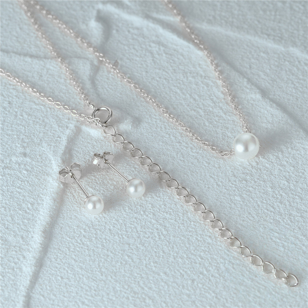 Silver necklace with pearl pendants on a light fabric background