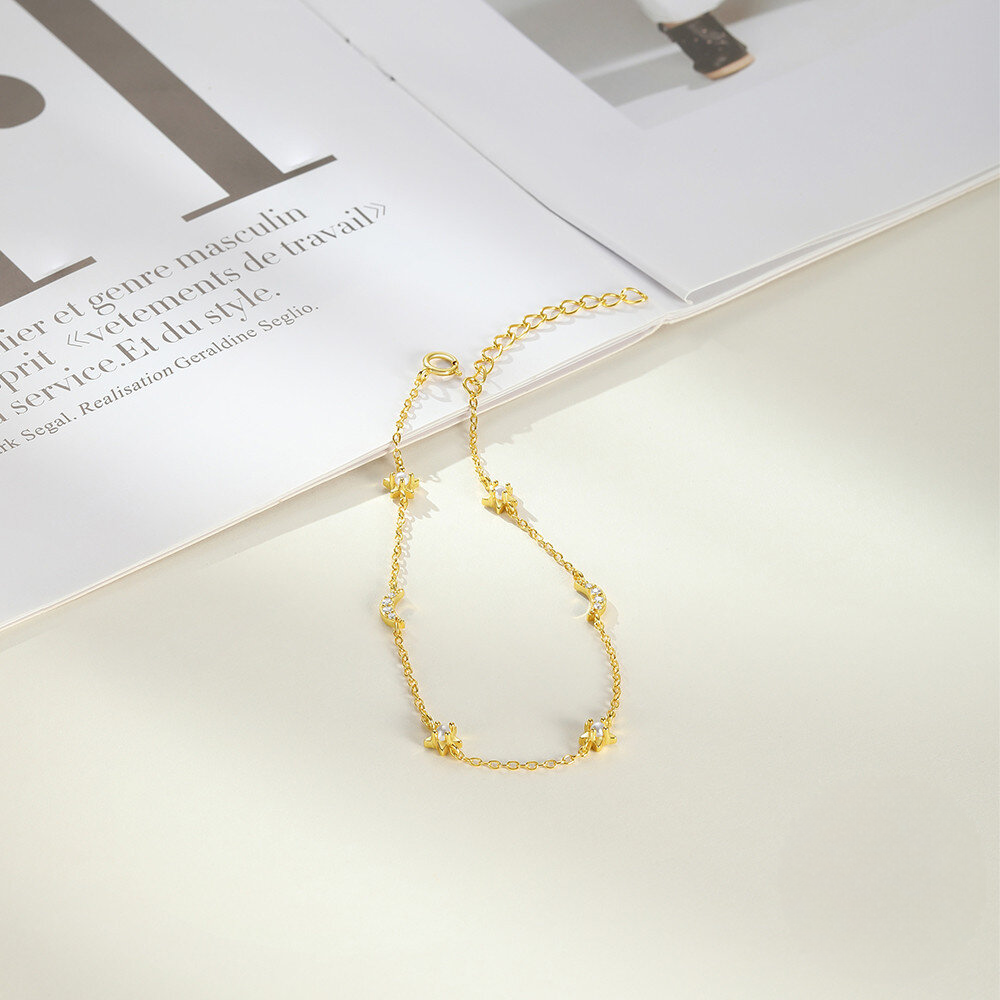 Gold necklace on a white surface with an open book in the background