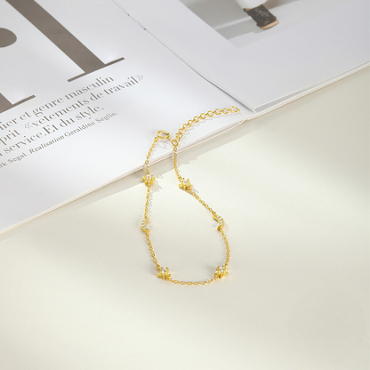 Gold necklace on a white surface with an open book in the background